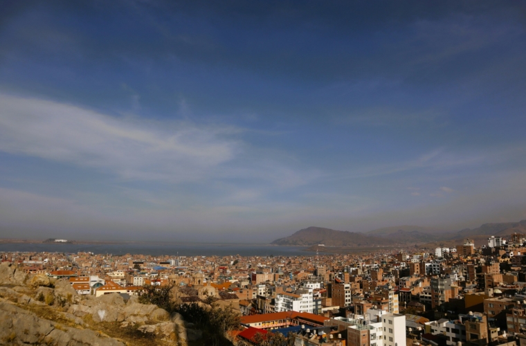 Vista panorámica de la ciudad de Puno con el lago Titicaca al fondo, mostrando la armonía entre el paisaje urbano y la belleza natural