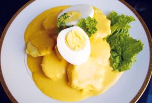 Foto de un plato de Papa a la Huancaína, con papas cocidas, salsa cremosa de ají amarillo, huevo duro, aceitunas y hojas de lechuga