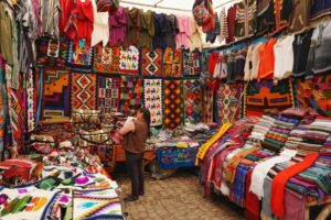 Tienda tradicional peruana llena de ropa colorida típica de la sierra, con prendas de invierno como ponchos, chullos y mantas